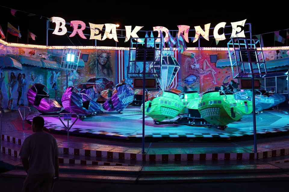 Karuzela Breakdance w kolorowych neonach na nocnym wesołym miasteczku